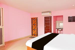 una camera da letto con pareti rosa, un letto e una porta di Super Hotel O Daba Gardens Near Dolphin Junction a Alipur