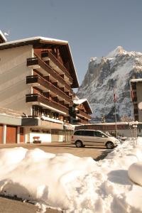 ein Auto, das vor einem Gebäude im Schnee parkt in der Unterkunft Hotel Residence in Grindelwald