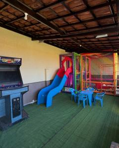 een speelkamer met een glijbaan, tafels en een videospel bij Pousada Vila Italia - Porto da Dunas in Aquiraz