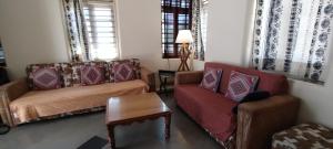 ein Wohnzimmer mit 2 Sofas und einem Tisch in der Unterkunft Madhav Bhavan Guest House in Pune