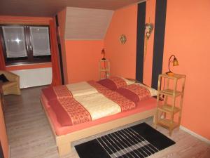 a bedroom with a bed with orange walls and a window at Ferienhaus Schulze in Schierke