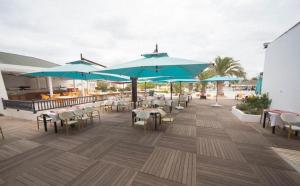 eine Terrasse mit Tischen, Stühlen und Sonnenschirmen in der Unterkunft Djerba Holiday Beach in Midoun