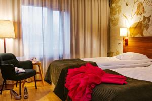 une chambre d'hôtel avec une robe rouge sur le lit dans l'établissement Scandic Gävle Väst, à Gävle