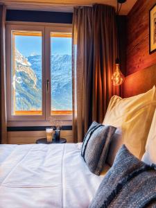 グリンデルワルトにあるBoutique Hotel Panorama Grindelwaldのベッドルーム1室(ベッド1台付)、山の景色を望む窓が備わります。