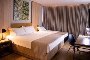 a hotel room with a large bed and a desk at Hotel Cassino Tower São José do Rio Preto by Nacional Inn in Sao Jose do Rio Preto