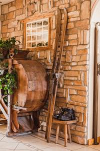 een houten vat naast een stenen muur bij Hotel Arnika in Pozza di Fassa