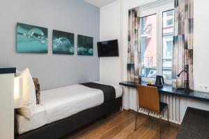 1 dormitorio con cama, escritorio y ventana en Hotel Bristol Zurich, en Zúrich