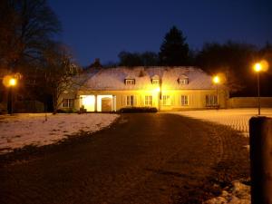 una casa illuminata di notte nella neve di Gästehaus Villa Wolff a Bomlitz