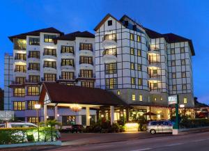 um grande edifício branco com carros estacionados em frente em Hotel De' La Ferns, Cameron Highlands em Cameron Highlands