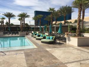 uma piscina com cadeiras e guarda-sóis e palmeiras em Luxury Suites International at The Signature em Las Vegas