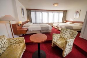 Cette chambre d'hôtel comprend deux lits, une table et des chaises. dans l'établissement Hotel Restaurant in den Hoof, à Maastricht