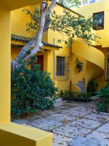 una casa gialla con un albero di fronte di Bungalows Demetria a Guadalajara