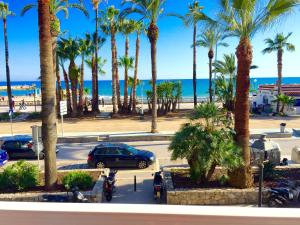 - une vue sur un parking avec des palmiers et l'océan dans l'établissement Sitges Seafront Ribera Apartment, à Sitges