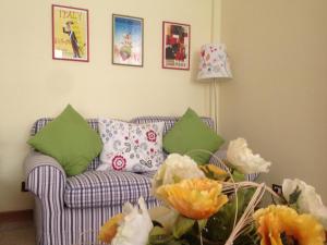 a living room with a couch with green pillows and flowers at Inn Rome B&B in Ciampino