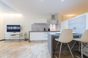 cocina con armarios blancos, mesa y sillas en Suites Garden Loft Picasso, en Las Palmas de Gran Canaria