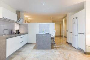 cocina con armarios blancos y encimera en Suites Garden Loft Picasso, en Las Palmas de Gran Canaria