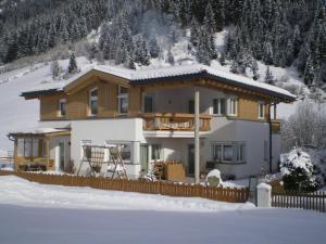 una casa grande con una valla en la nieve en Alpina Appartement, en Sankt Leonhard im Pitztal