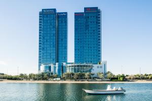 ein Boot im Wasser vor einer Stadt in der Unterkunft Ibis Abu Dhabi Gate in Abu Dhabi