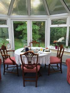 een eetkamer met een tafel, stoelen en ramen bij Kingswood Cottage in Lyndhurst