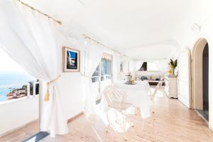 um quarto branco com uma mesa e cadeiras e o oceano em Villa Flavio Gioia em Positano