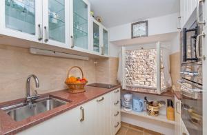 una cucina con armadi bianchi e lavandino di Holiday Home Piccolo Mondo a Dubrovnik