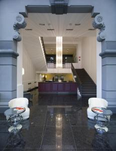 un grand hall avec deux chaises et un escalier dans l'établissement Italiana Hotels Milan Rho Fair, à Rho