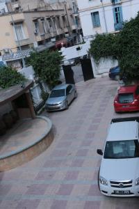 dwa samochody zaparkowane na parkingu obok budynków w obiekcie Hotel Saint Georges Tunis w mieście Tunis