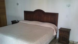 a bedroom with a bed with a wooden headboard and a nightstand at Hotel Real de Cuautla in Cuautla Morelos