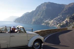 Un uomo che guida un'auto bianca su una strada di montagna di Hotel Poseidon a Positano