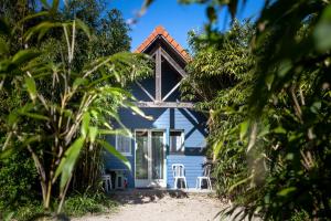 una casa blu vista tra gli alberi di Naturotel a Fort-Mahon-Plage