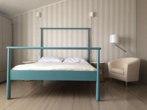 een bed met een blauw frame en een stoel in een kamer bij Guest House Vasara in Nida