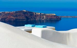 two blue towels sitting on a table overlooking the ocean at White Santorini in Imerovigli