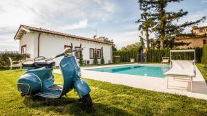 een blauwe scooter geparkeerd in het gras naast een zwembad bij Podere Villa Olmo in Pistoia