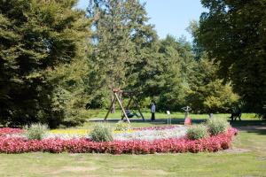 un parc avec une aire de jeux fleurie et une balançoire dans l'établissement Ringhotel Fährhaus, à Bad Bevensen