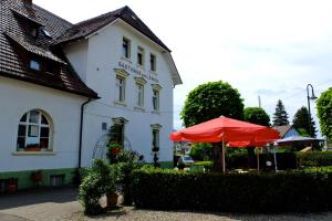 un edificio blanco con un paraguas rojo delante de él en Hotel Löwen, en Kirchzarten