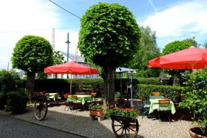 un jardín con mesas, sillas y sombrillas rojas en Hotel Löwen, en Kirchzarten