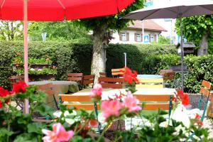 una mesa y sillas con una sombrilla roja y flores en Hotel Löwen, en Kirchzarten