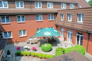 an umbrella in front of a building with a patio at Hotel Maack in Seevetal