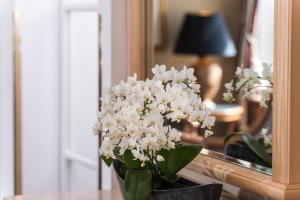 un vase de fleurs blanches devant un miroir dans l'établissement Hotel Am Jägertor, à Potsdam