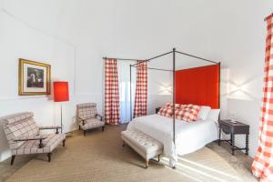 um quarto com uma cama de dossel e uma cadeira em Casa Rural Castillo de Cáceres em Cáceres