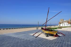 um pequeno barco sentado num passeio junto ao oceano em Apulia Praia Hotel em Esposende