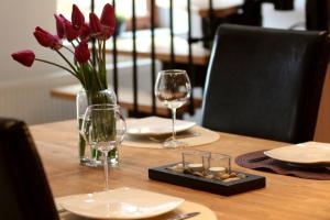 a table with two glasses and a vase of red flowers at Haus Winkelchen in Cochem