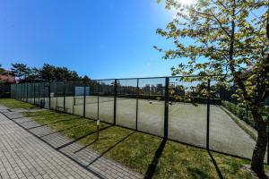 een tennisbaan voor een hek bij Nida Vėtrungių 3 , apartamentai in Nida