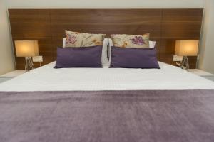 1 dormitorio con 1 cama grande con almohadas moradas en Manolia City Residences, en Nicosia