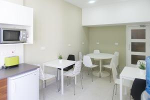 cocina y comedor con mesas y sillas blancas en Manolia City Residences, en Nicosia