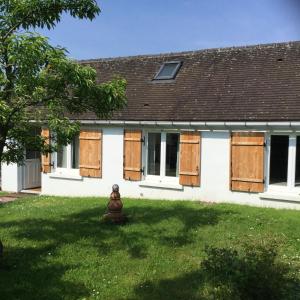 een wit huis met houten luiken en een tuin bij La Maisonnette de Senlis in Senlis