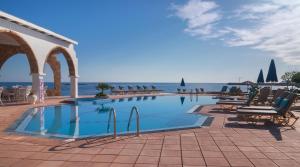 una piscina con sedie e l'oceano sullo sfondo di Pyrgos Beach Hotel Apartments a Mália