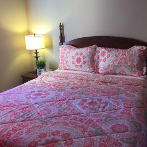 1 dormitorio con cama con colcha y almohadas rosas en The Falls Family Lodge, en Niagara Falls