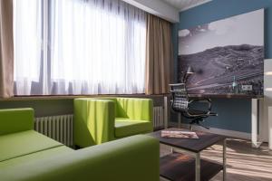 salon z zielonymi krzesłami i stołem w obiekcie ibis Styles Offenburg City w mieście Offenburg