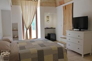 a bedroom with a bed and a tv on a dresser at Dimora Dioniso in Polignano a Mare